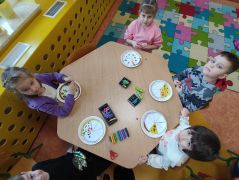 Dzieciaki dodają składniki do pizzy.