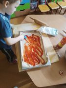 Chłopiec smaruje ciasto sosem pomidorowem.