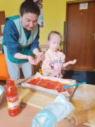 Pani z dziewczynką sypią na ciasto przyprawę.