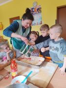 Pani z dziećmi przygotowuje pizzę.