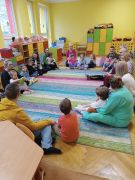 Dzieci z Rodzicami na dywanie.
