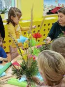 Dzieci z rodzicami tworzą palmy wielkanocne.