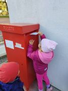 Dziewczynka wrzuca kartkę do skrzynki pocztowej 