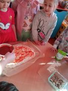 Dzieci smarują pizzę sosem