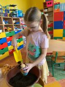 dziewczynka przysypuje zasadzoną cebulę