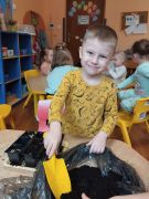 chłopiec przysypuje nasiona ziemią