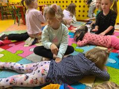 Dzieci leżą na dywanie i wykonuje sobie nawzajem masażyki