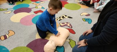 Dziecko uczy się masażu serca na fantomie.