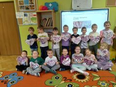 Dzieci pozują z sercami do zdjęcia.