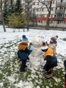 Dzieci lepią misia ze śniegu.