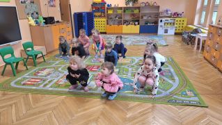 Dzieci kucają na dywanie.