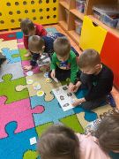 Dzieci wykonują zadanie na dywanie.