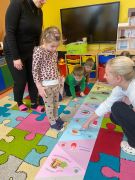 Dzieci wykonują zadanie na dywanie.