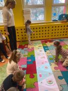 Dzieci wykonują zadanie na dywanie.