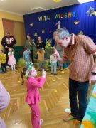 Dzieci tańczą z rodzicami do muzyki.