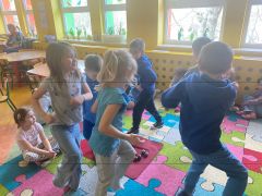 Dzieci tańczą na dywanie.