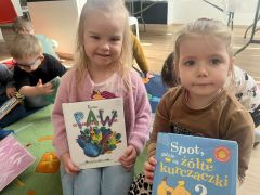 Dziewczynki pozują do zdjęcia z książkami.